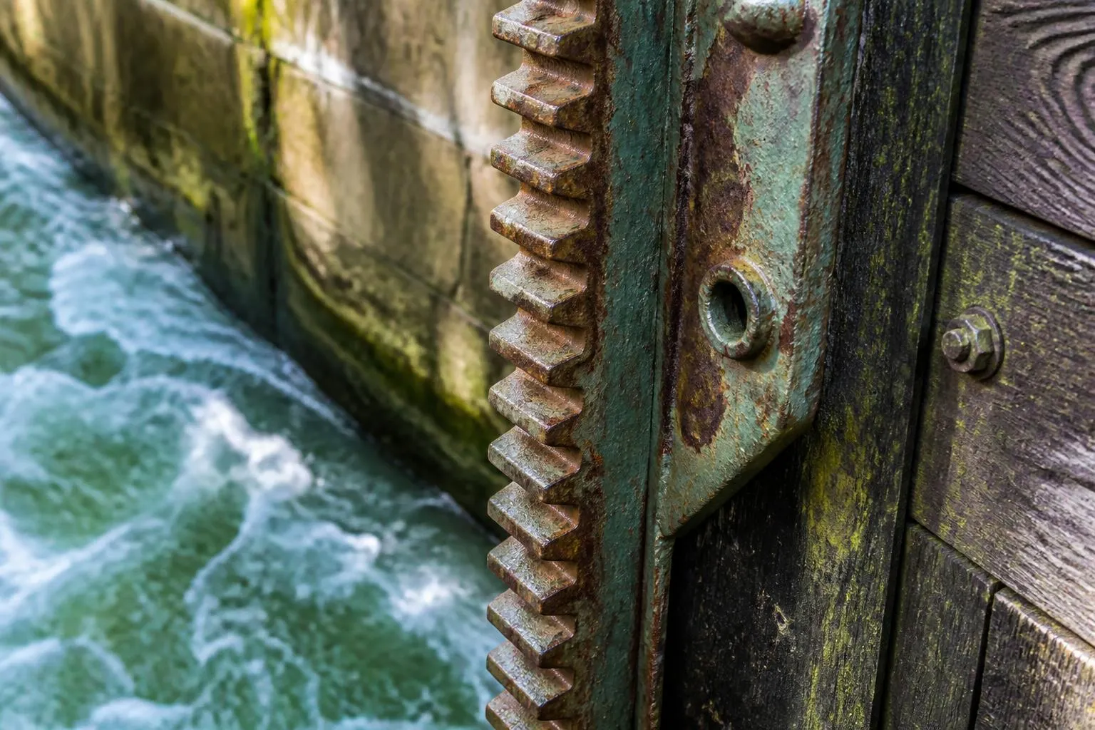 Vantelle et sa crémaillère sur la porte busquée d’une écluse de canal, eau bouillonnant au pied du bajoyer